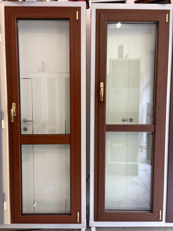 Due porte in vetro con cornice marrone e maniglie dorate esposte in uno showroom ben illuminato.
