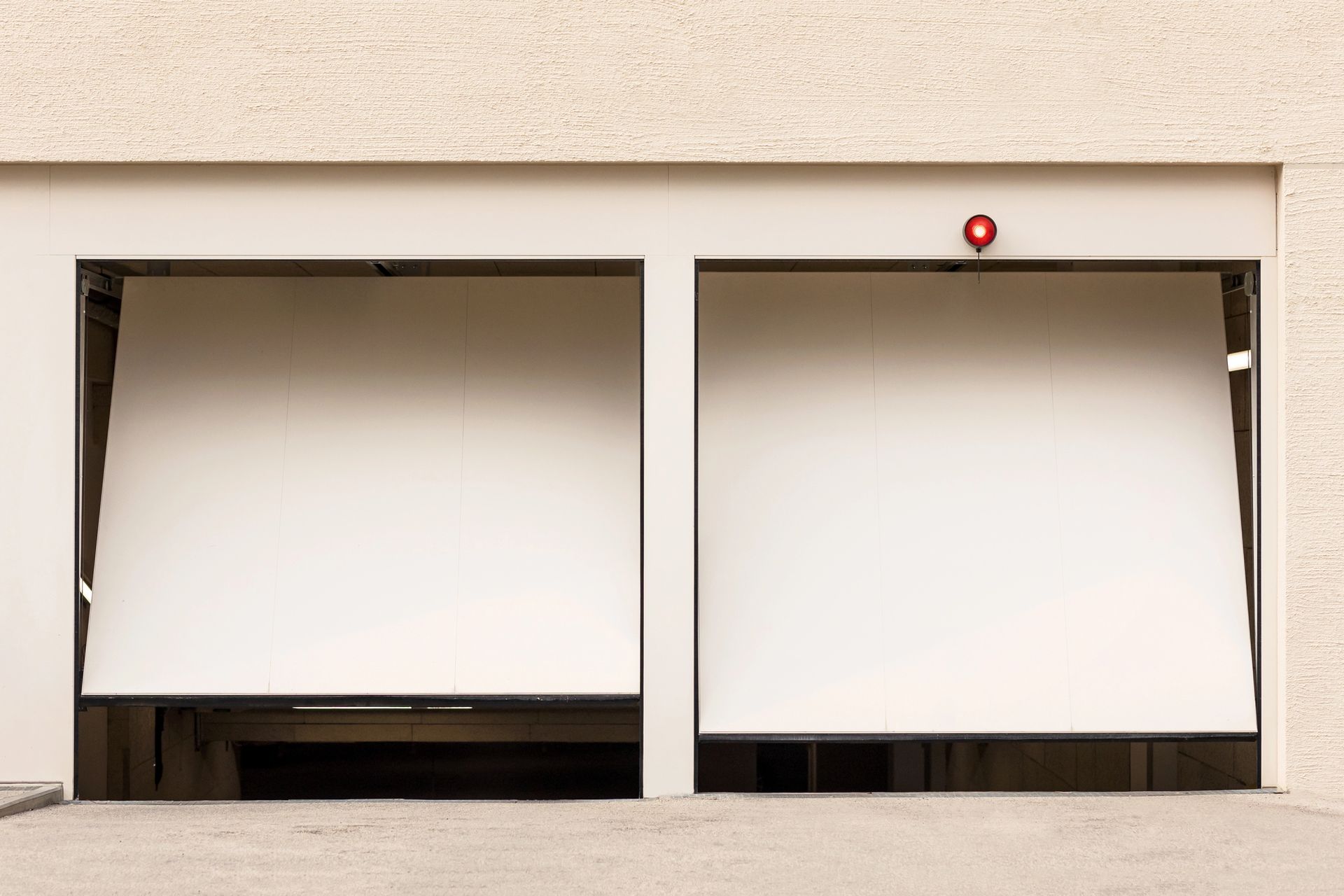 Due porte bianche del garage sono aperte, rivelando l'interno del garage. Una luce rossa è accesa sopra la porta di destra.