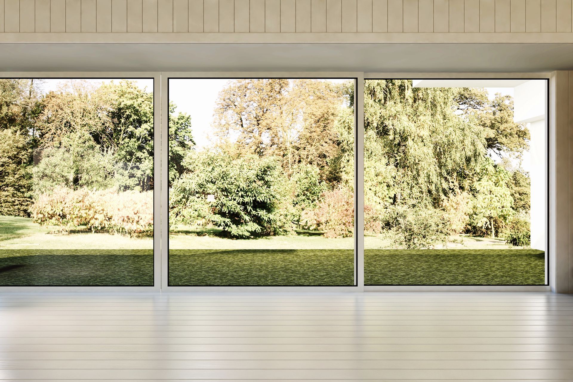 Camera con pareti bianche e ampie finestre che si affacciano su un cortile verde e alberi colorati.