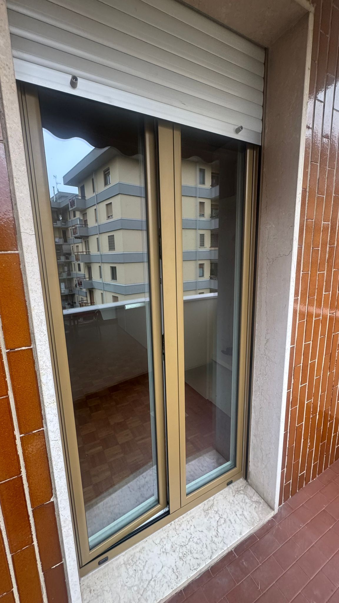Le porte scorrevoli in vetro si aprono su un balcone con vista su un edificio.