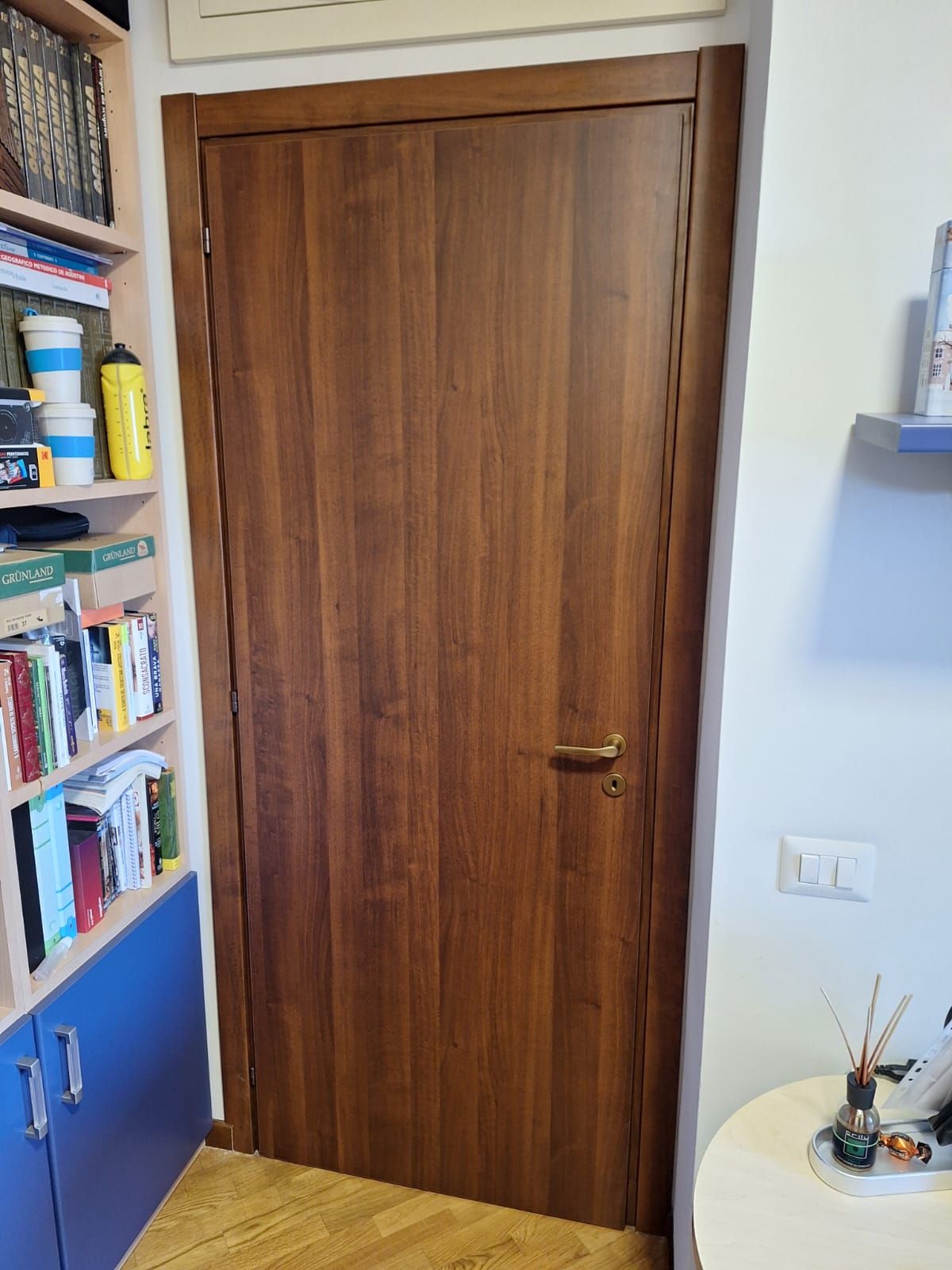Porta in legno con finitura marrone scuro, maniglia in ottone e telaio di colore chiaro.