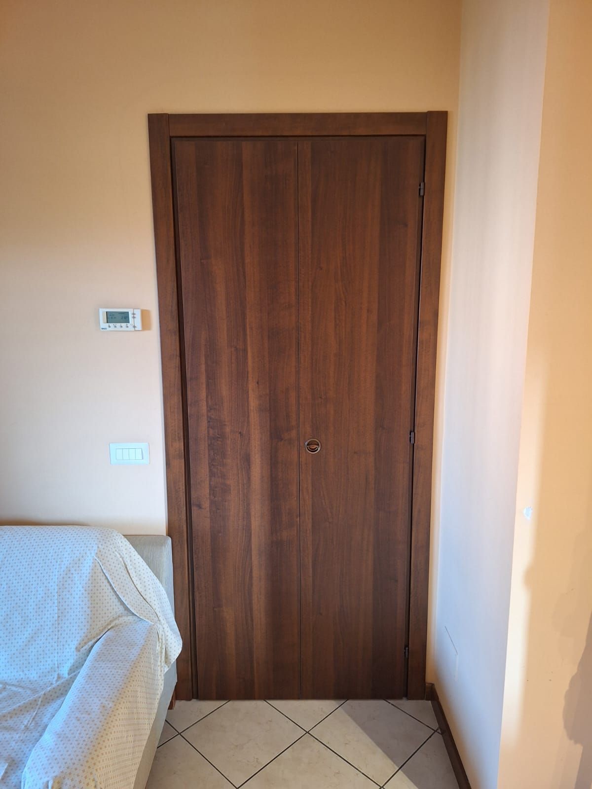 Porta a due battenti in legno con cornice marrone, incastonata in una parete dipinta di arancione. 