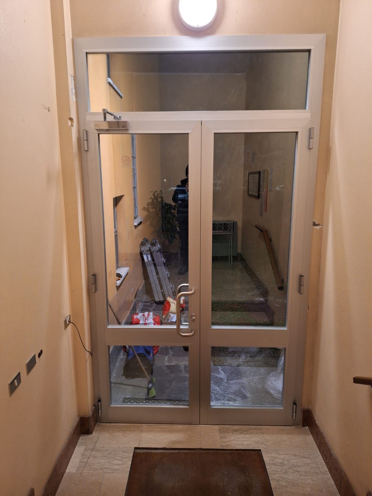 Doppie porte in vetro con finestra a traverso conducono all'interno di un edificio.