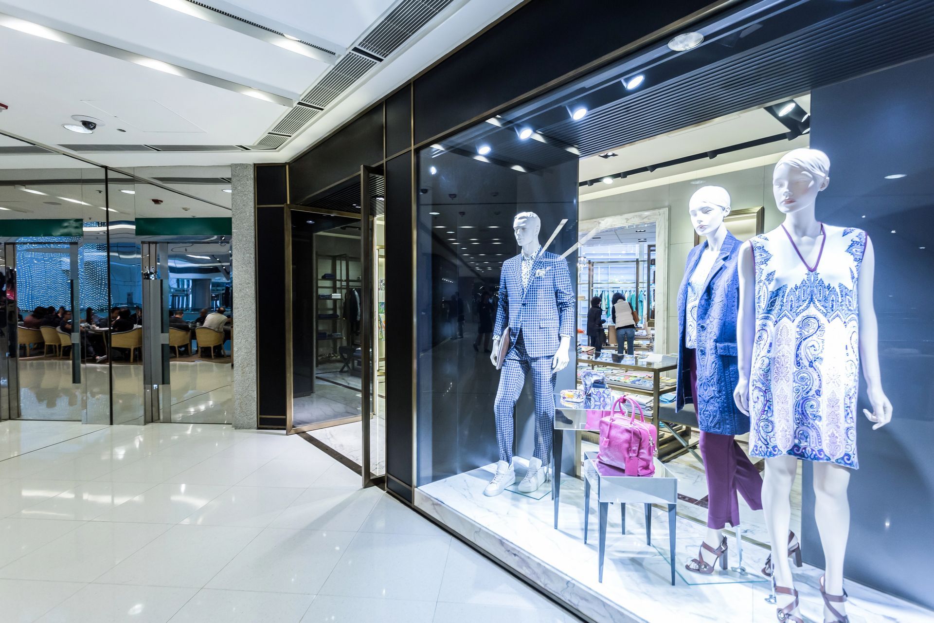 Vetrina con manichini che espongono abiti all'interno di un centro commerciale.