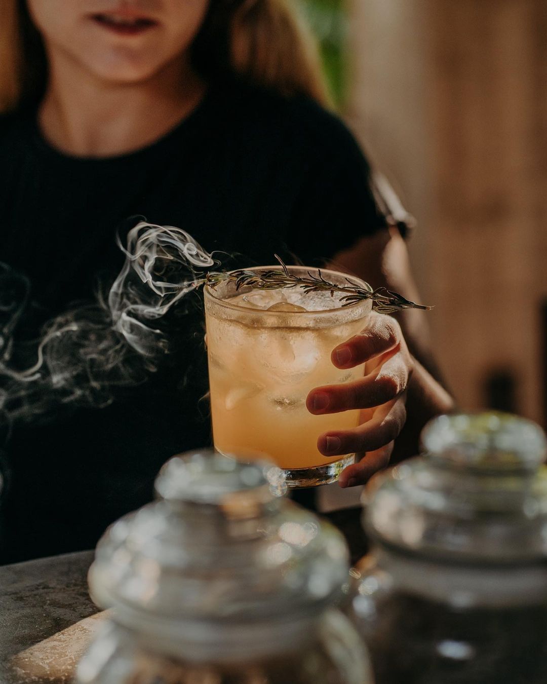 A woman is holding a drink in her hand with smoke coming out of it.