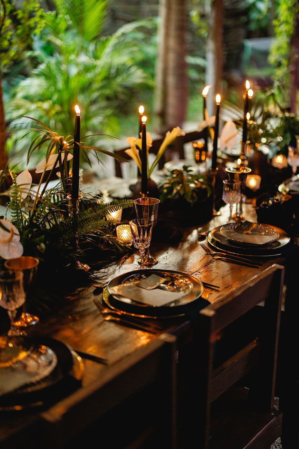 A table with plates , glasses , and candles on it.