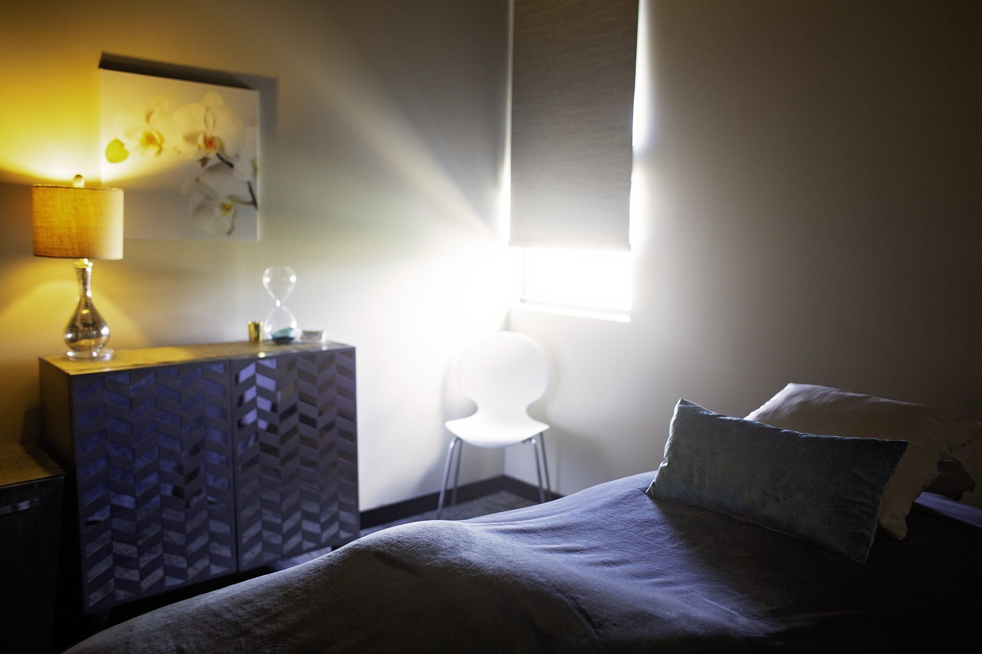 A bedroom with a bed a dresser and a lamp