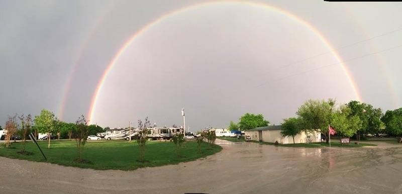Double rainbow over a campground with green grass and buildings.