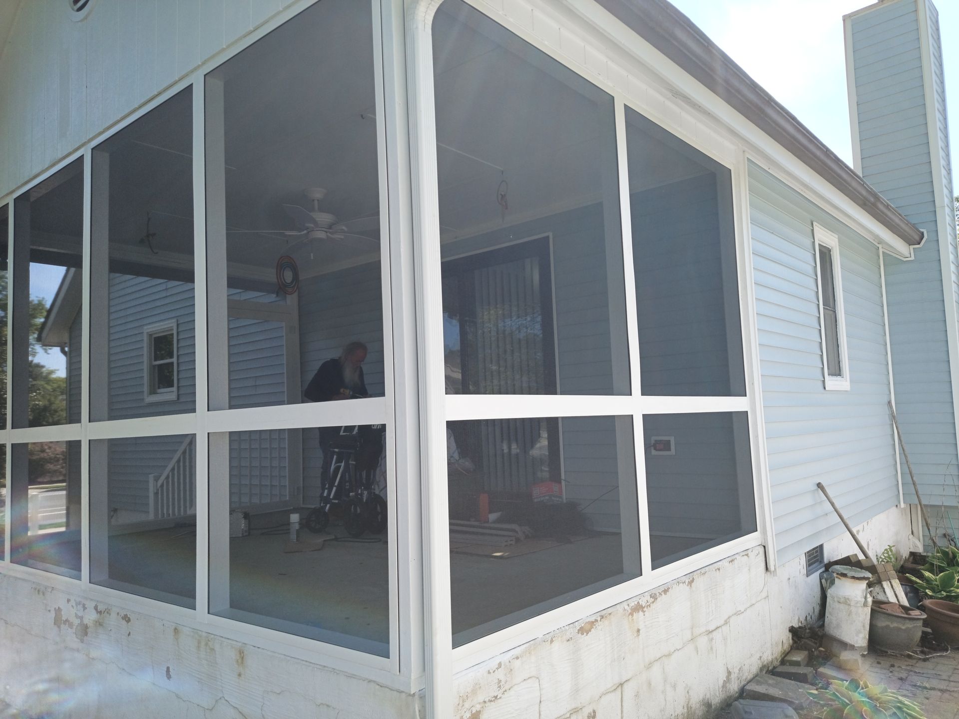 Screened porch with white trim on a light blue house, viewed from the corner.