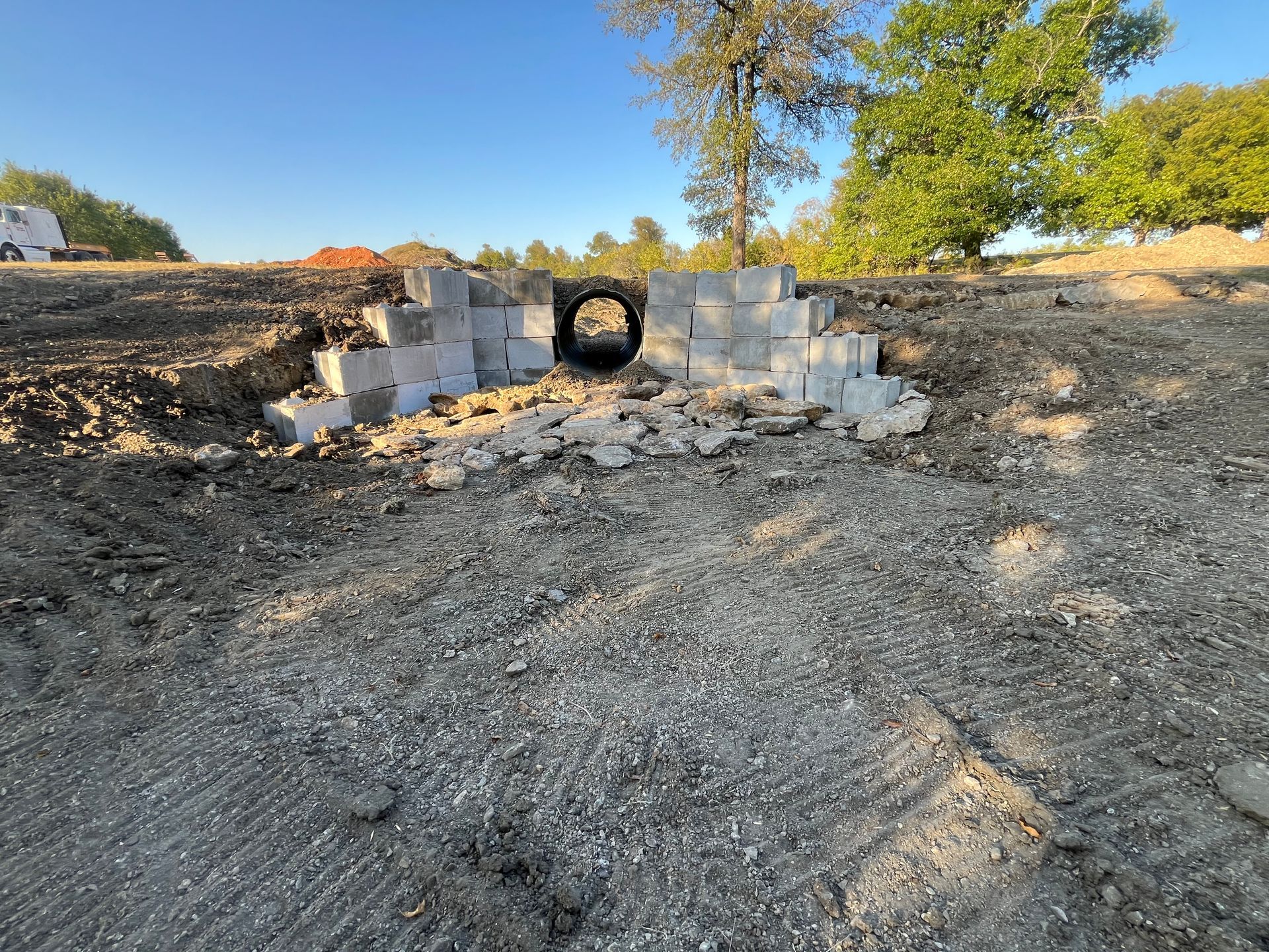 A drainage tunnel built with concrete blocks, under a dirt embankment. Sunny day.