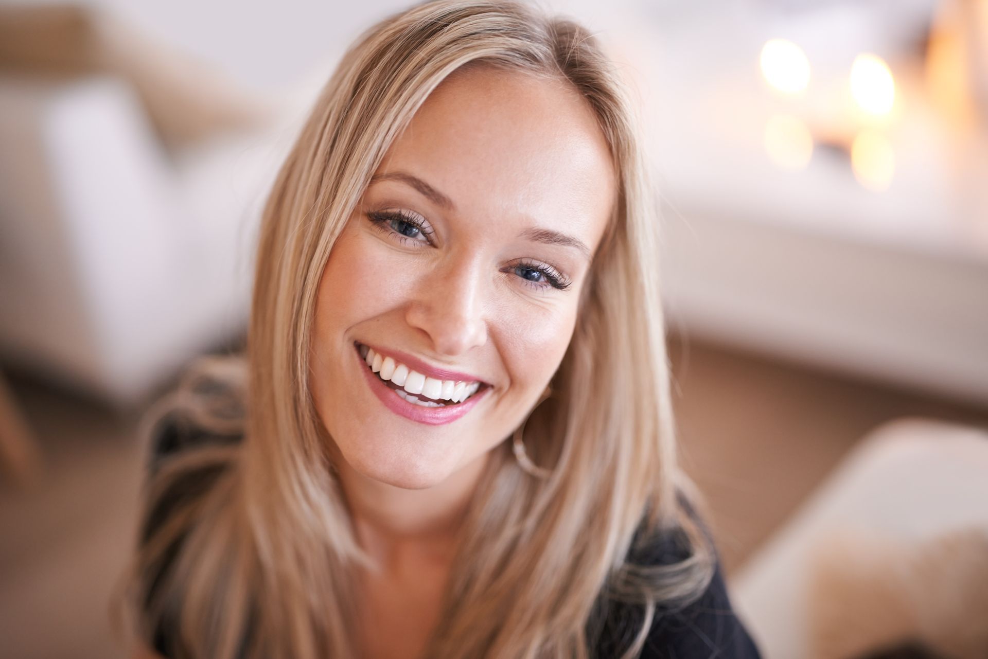 A woman is smiling for the camera in a living room.