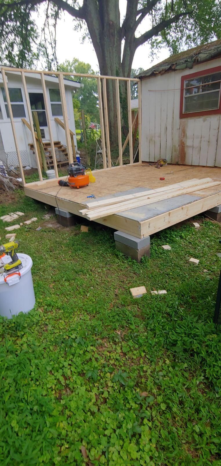 A wooden deck is being built in front of a shed.