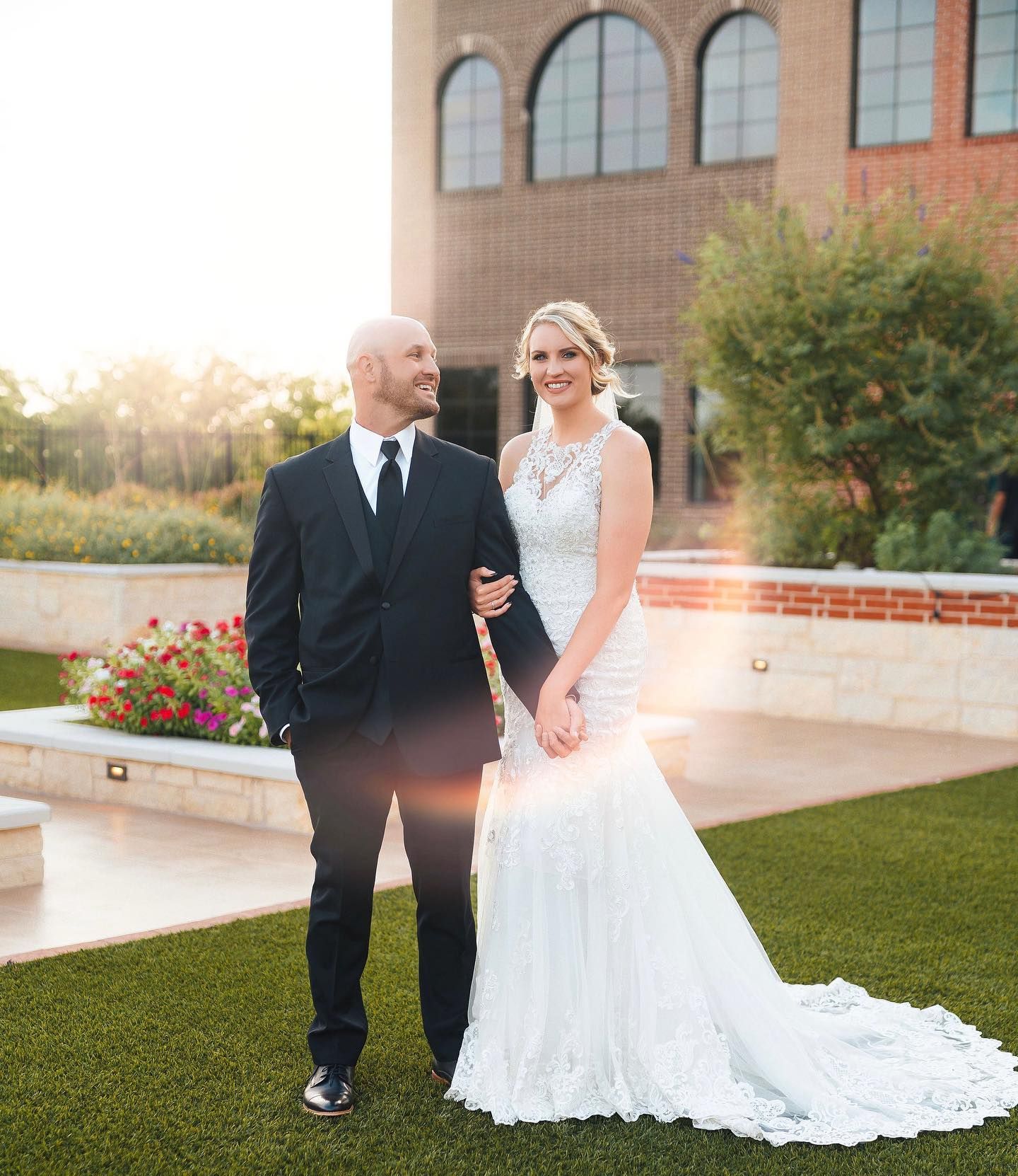 A bride and groom are posing for a picture in front of a building.