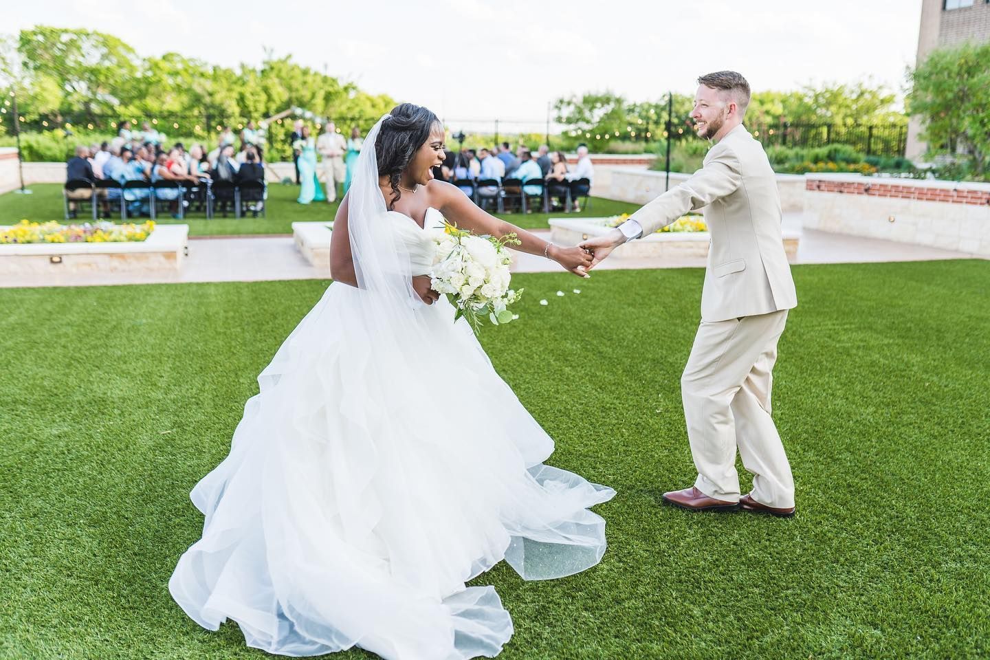 A bride and groom are dancing on a lush green field.