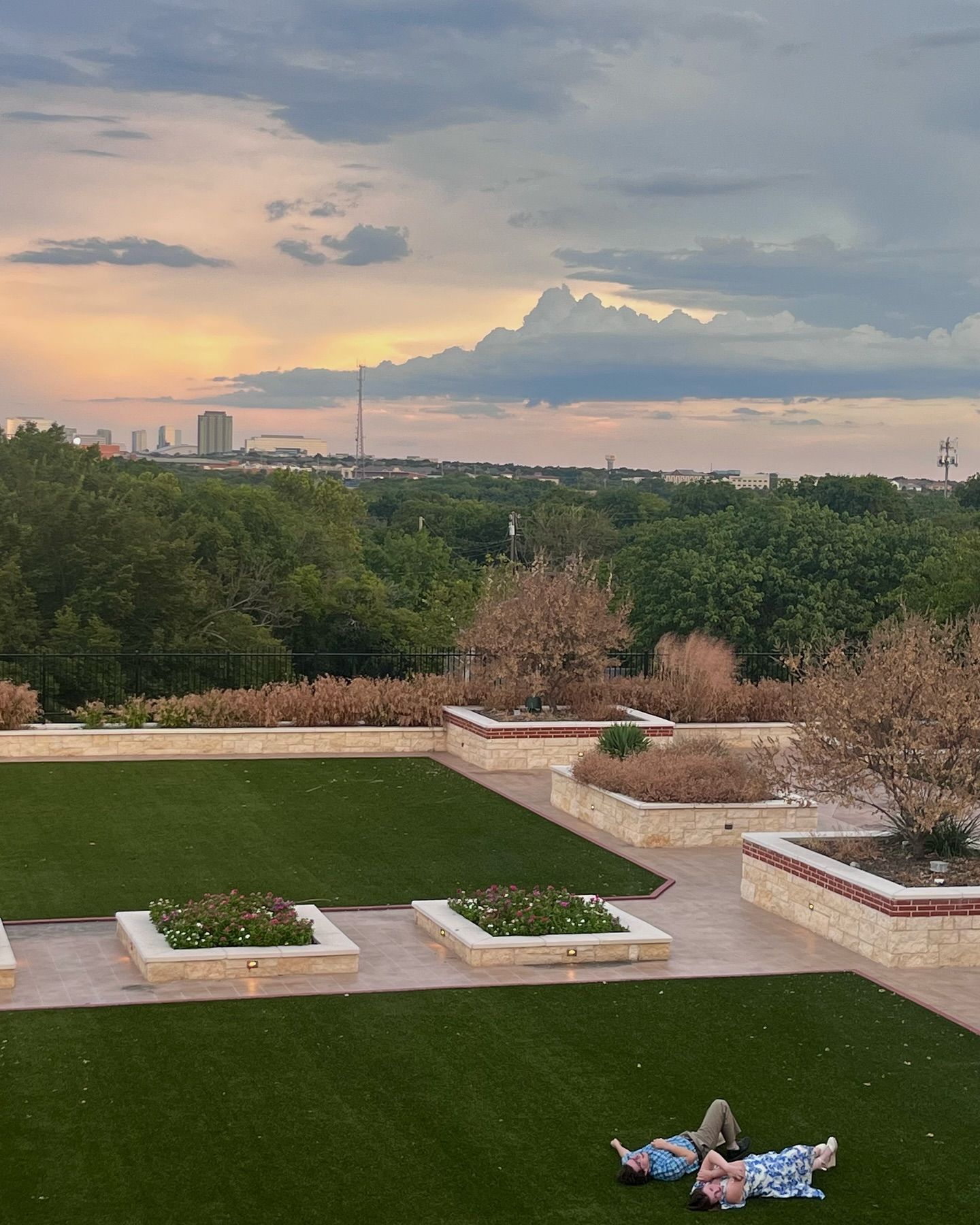 A couple laying on the grass in a park at sunset