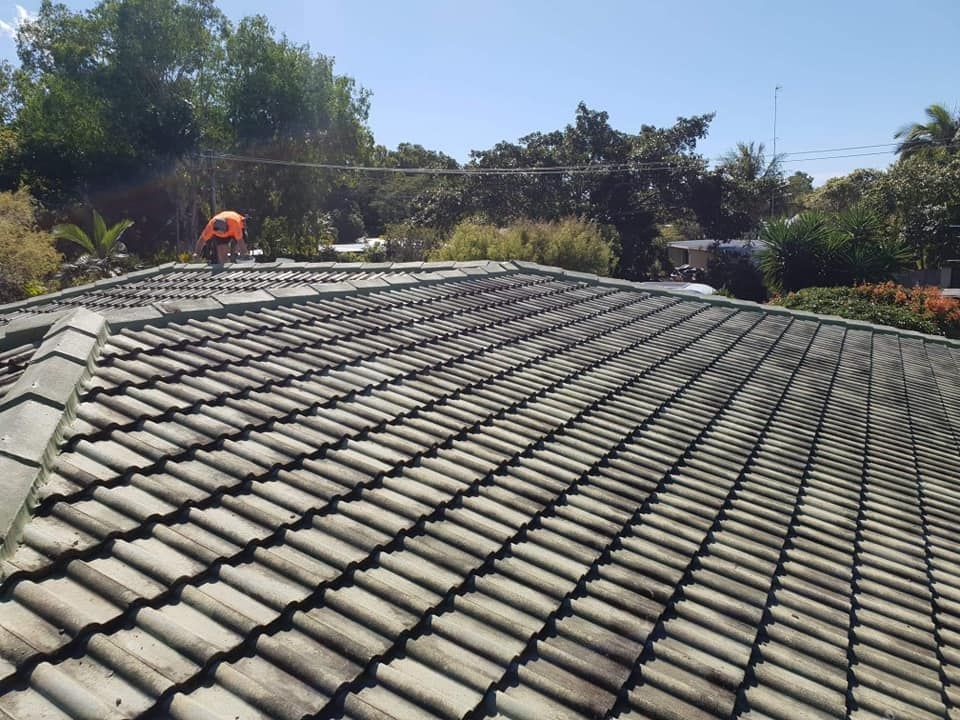Roofer in Orange Safety Gear on A Weathered Tile Roof Under a Sunny Sky — High Performance Roof Tiling P/L in Kewarra Beach, QLD