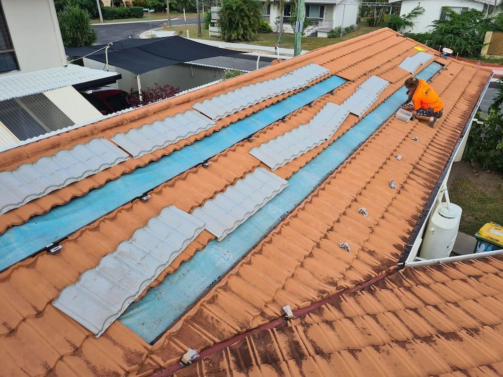 A Man is Working on the Roof of a House — High Performance Roof Tiling P/L in Innisfail, QLD