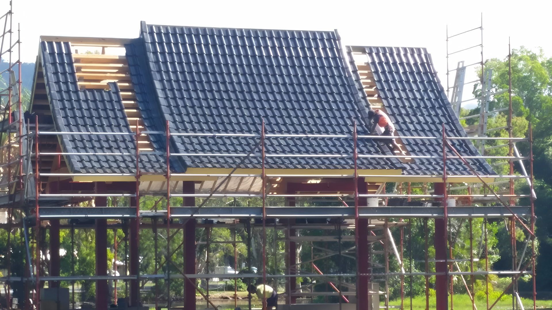 Construction Worker on Scaffolding Installing Dark Roof — High Performance Roof Tiling P/L in Kewarra Beach, QLD
