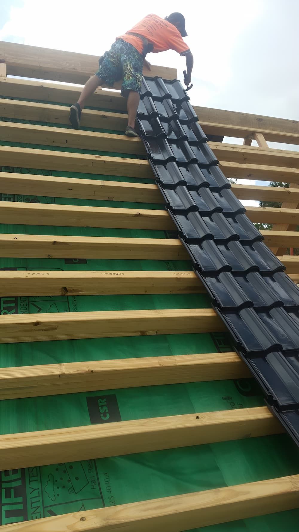 A Man is Standing on Top of a Wooden Roof — High Performance Roof Tiling P/L in Kewarra Beach, QLD