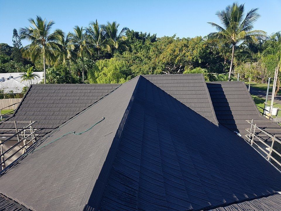 Dark Gray Roof Against a Backdrop of Green Trees and Palm Trees — High Performance Roof Tiling P/L in Kewarra Beach, QLD