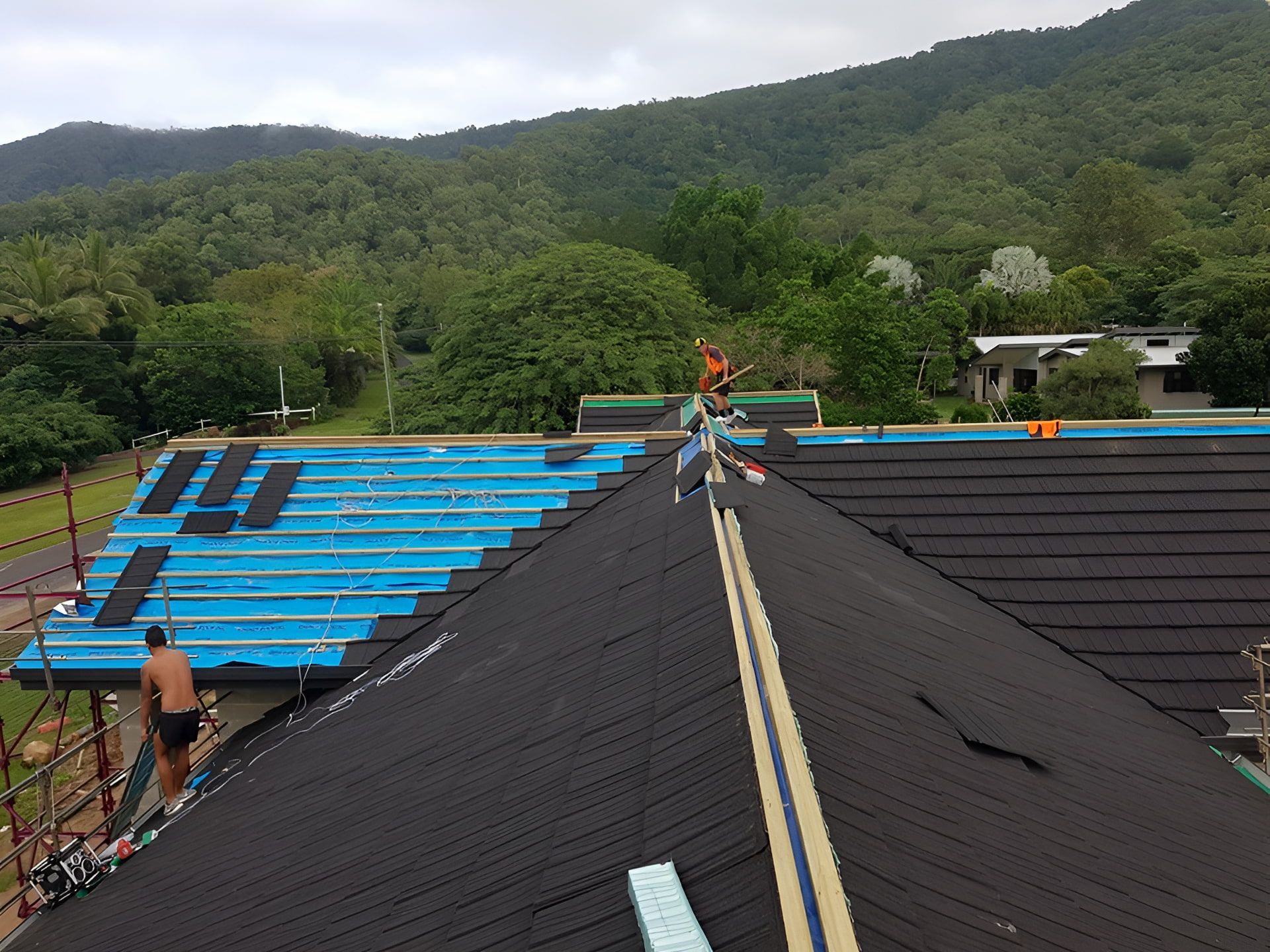 Roofers Installing Black Roofing Tiles; Blue Underlayment Exposed — High Performance Roof Tiling P/L in Kewarra Beach, QLD