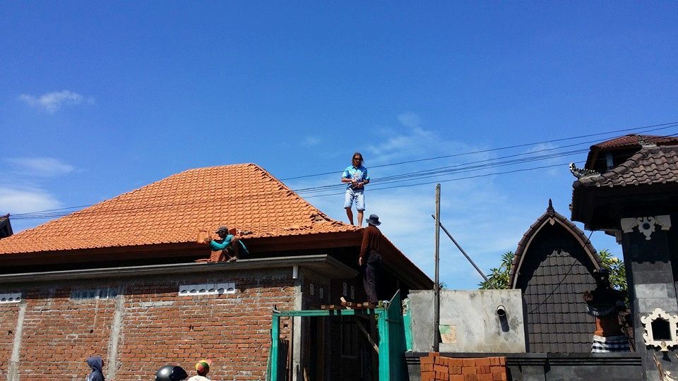 Men Working on A Terracotta-Tiled Roof Under a Bright Blue Sky — High Performance Roof Tiling P/L in Kewarra Beach, QLD