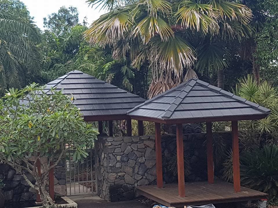 A Wooden Gazebo With a Slate Roof is Surrounded by Palm Trees — High Performance Roof Tiling P/L in Innisfail, QLD
