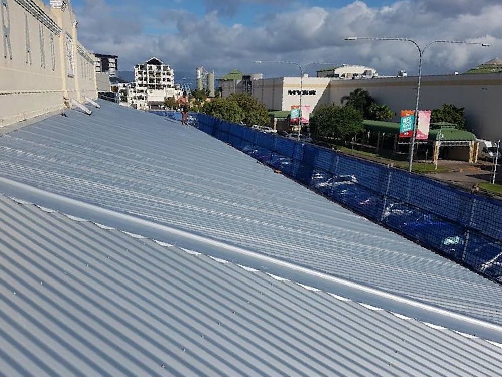 The Roof of a Building With a Blue Fence Around It — High Performance Roof Tiling P/L in Kewarra Beach, QLD