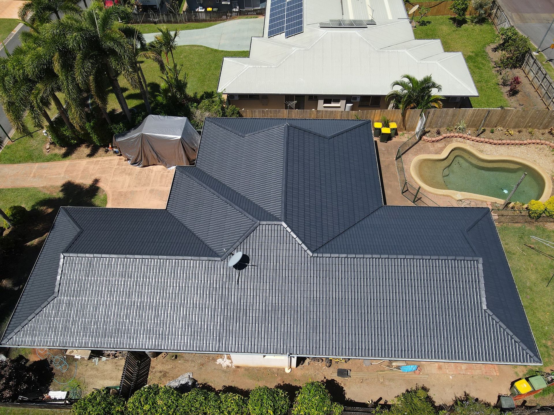 Aerial View of A Dark Gray Metal Roof on A House with A Pool — High Performance Roof Tiling P/L in Kewarra Beach, QLD
