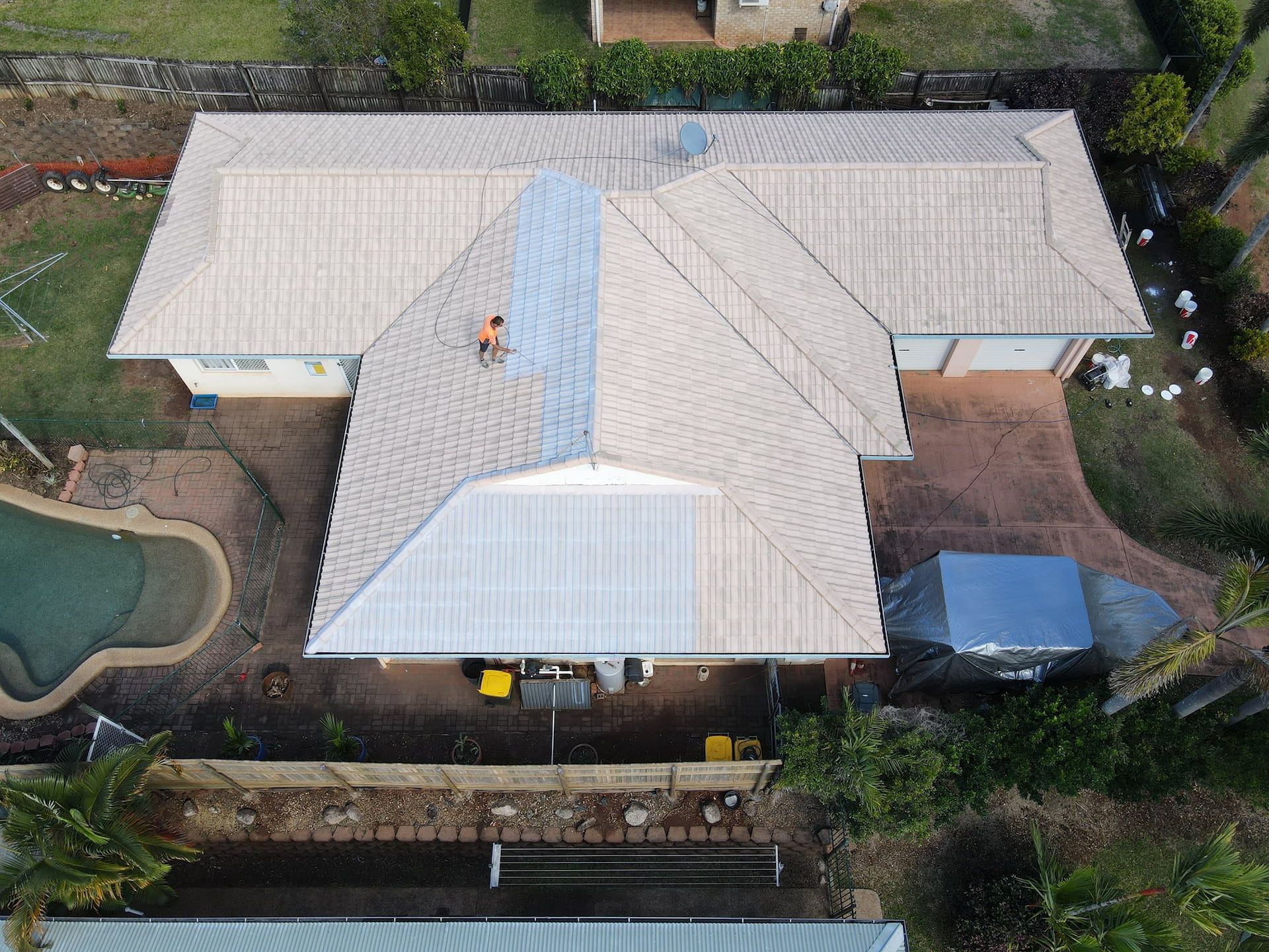 Aerial View of A House with A Person on The Roof, Partially Cleaned — High Performance Roof Tiling P/L in Kewarra Beach, QLD