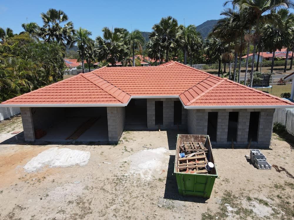 An Aerial View of a House Under Construction With a Green Dumpster in Front of It — High Performance Roof Tiling P/L in Port Douglas, QLD