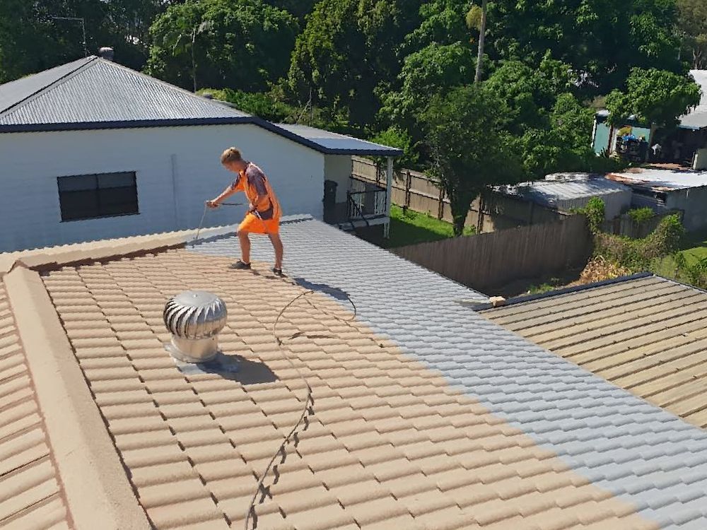 A Man is Standing on Top of a Tiled Roof — High Performance Roof Tiling P/L in Kewarra Beach, QLD