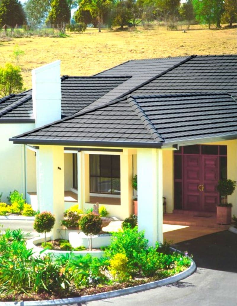 House with Black Tiled Roof, Beige Walls, and Red Front Door — High Performance Roof Tiling P/L in Kewarra Beach, QLD