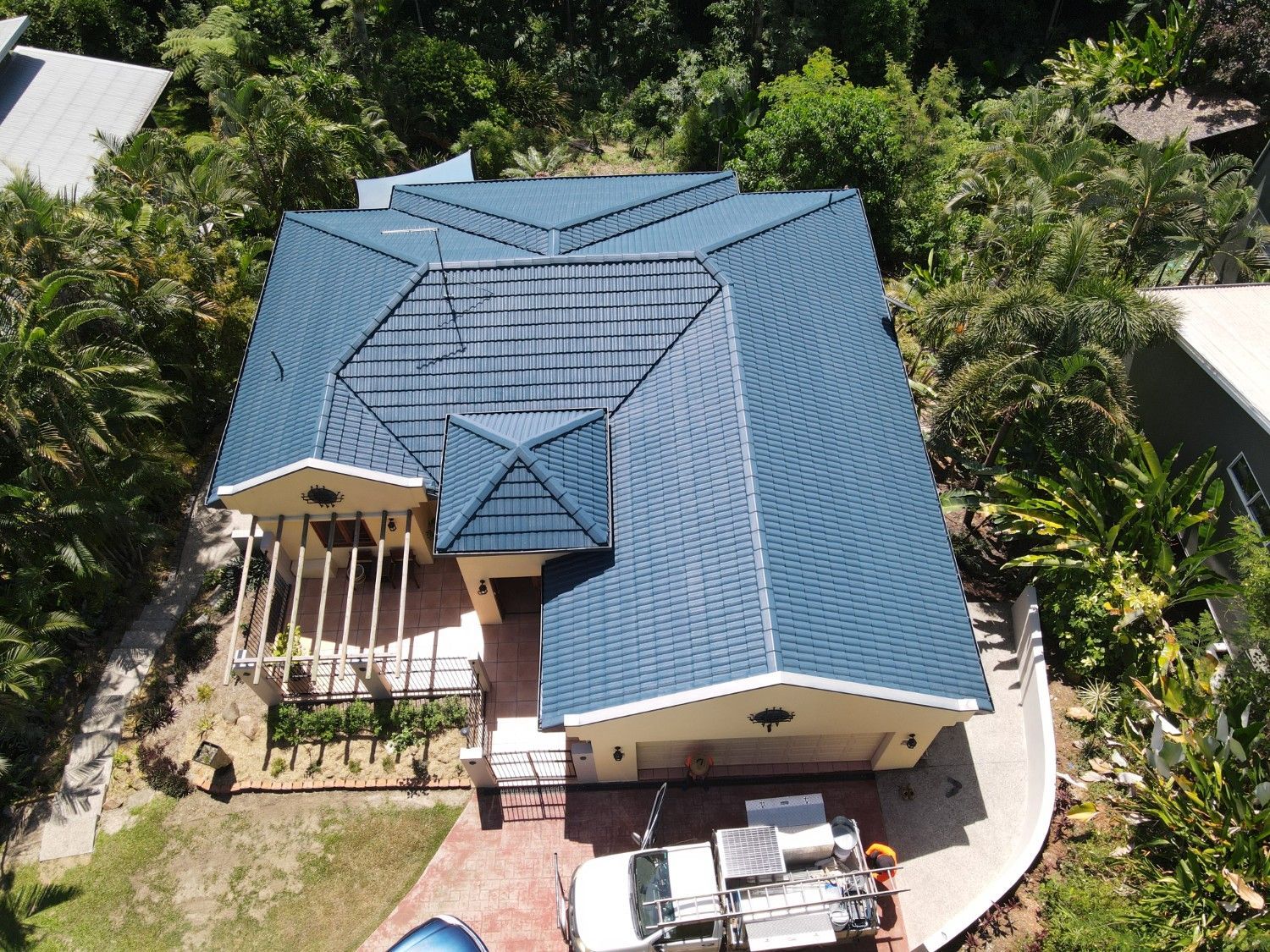 Blue-Roofed House with A White Porch, Surrounded by Green Trees — High Performance Roof Tiling P/L in Kewarra Beach, QLD