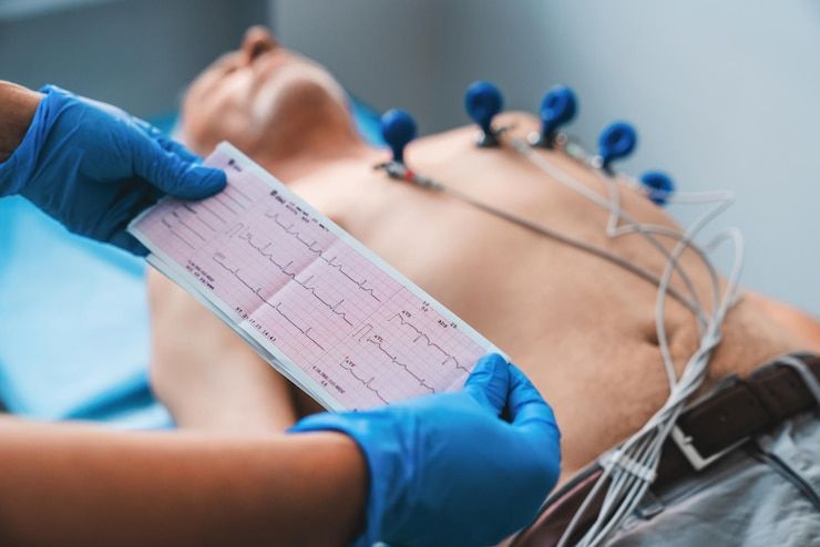 Person undergoing an electrocardiogram (ECG) test. Healthcare worker holds ECG printout.
