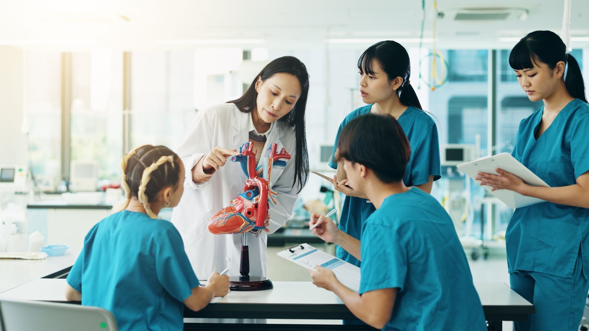 Medical professionals examining a heart model in a lab.