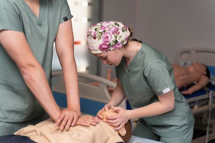 Two healthcare professionals practicing CPR on a medical dummy.