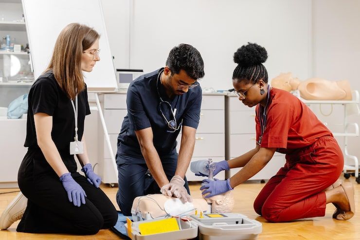 Three people practicing CPR on a medical dummy during a training session.