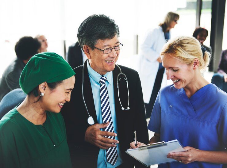 Doctor and nurse reviewing paperwork with smiling patient, in a medical setting.