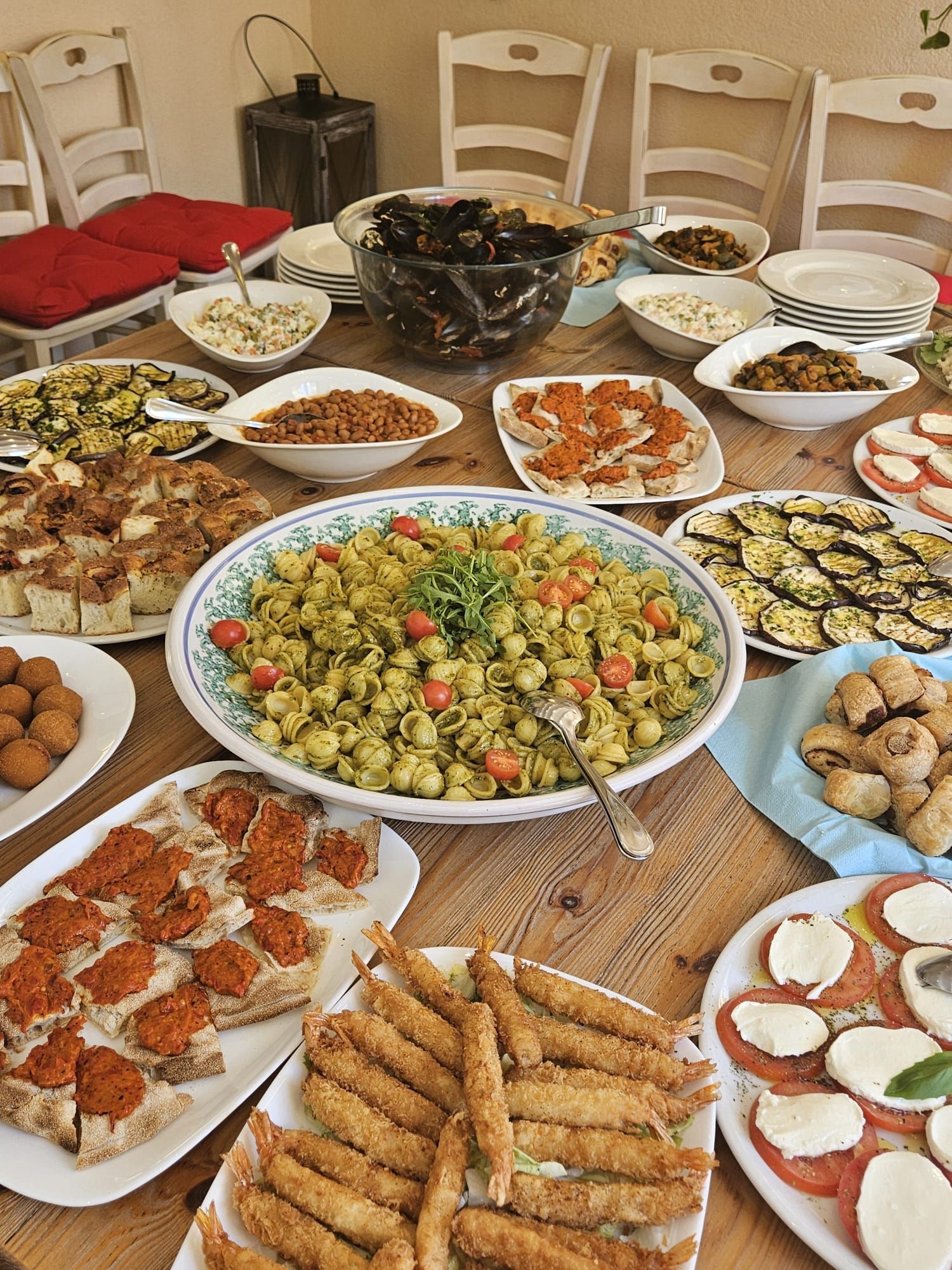 Ein Tisch voller Vorspeisen, Pasta, Gemüse und frittierten Fischgerichten für ein gemeinsames Essen.