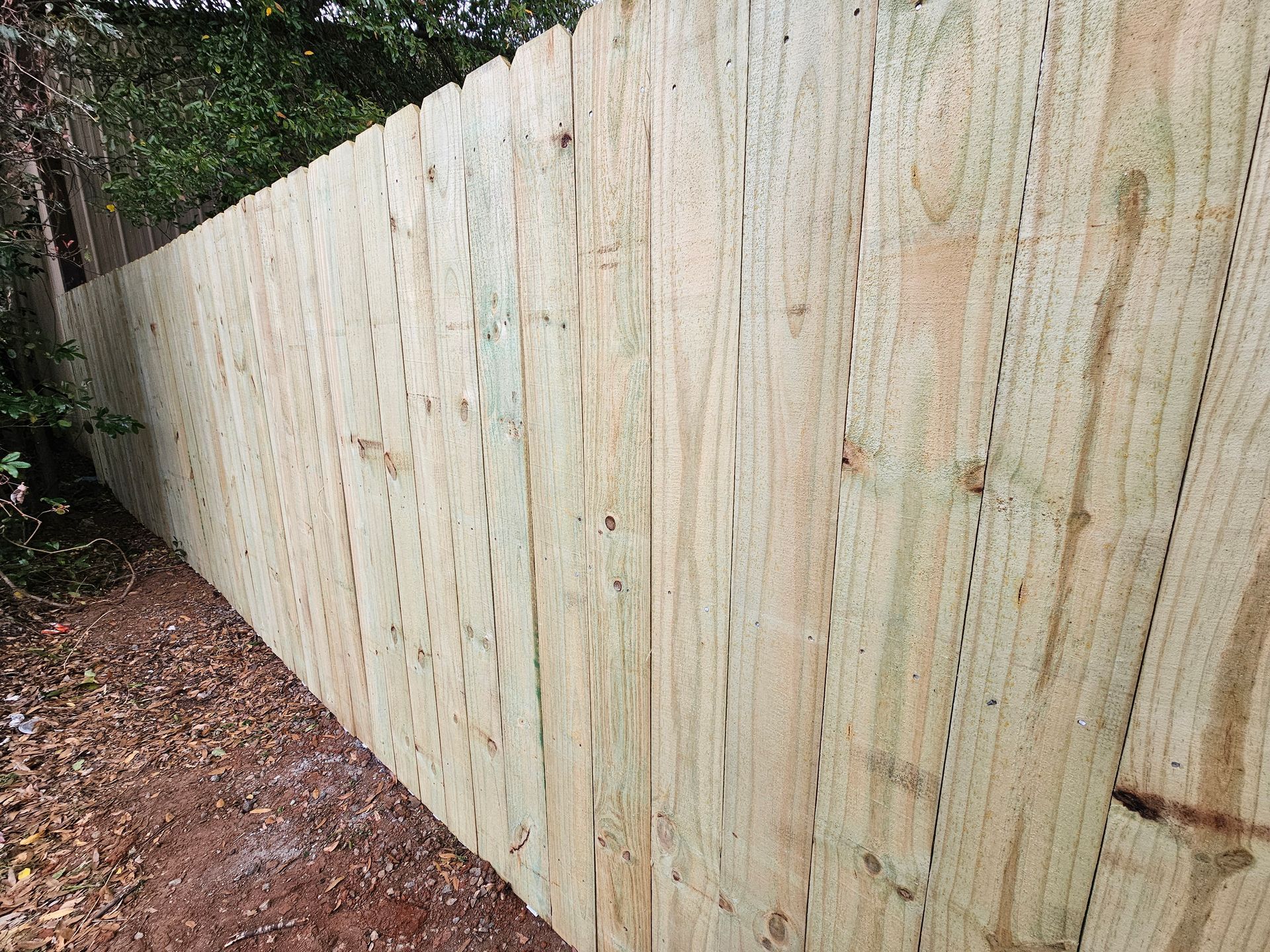 A long wooden fence is sitting on top of a dirt path.