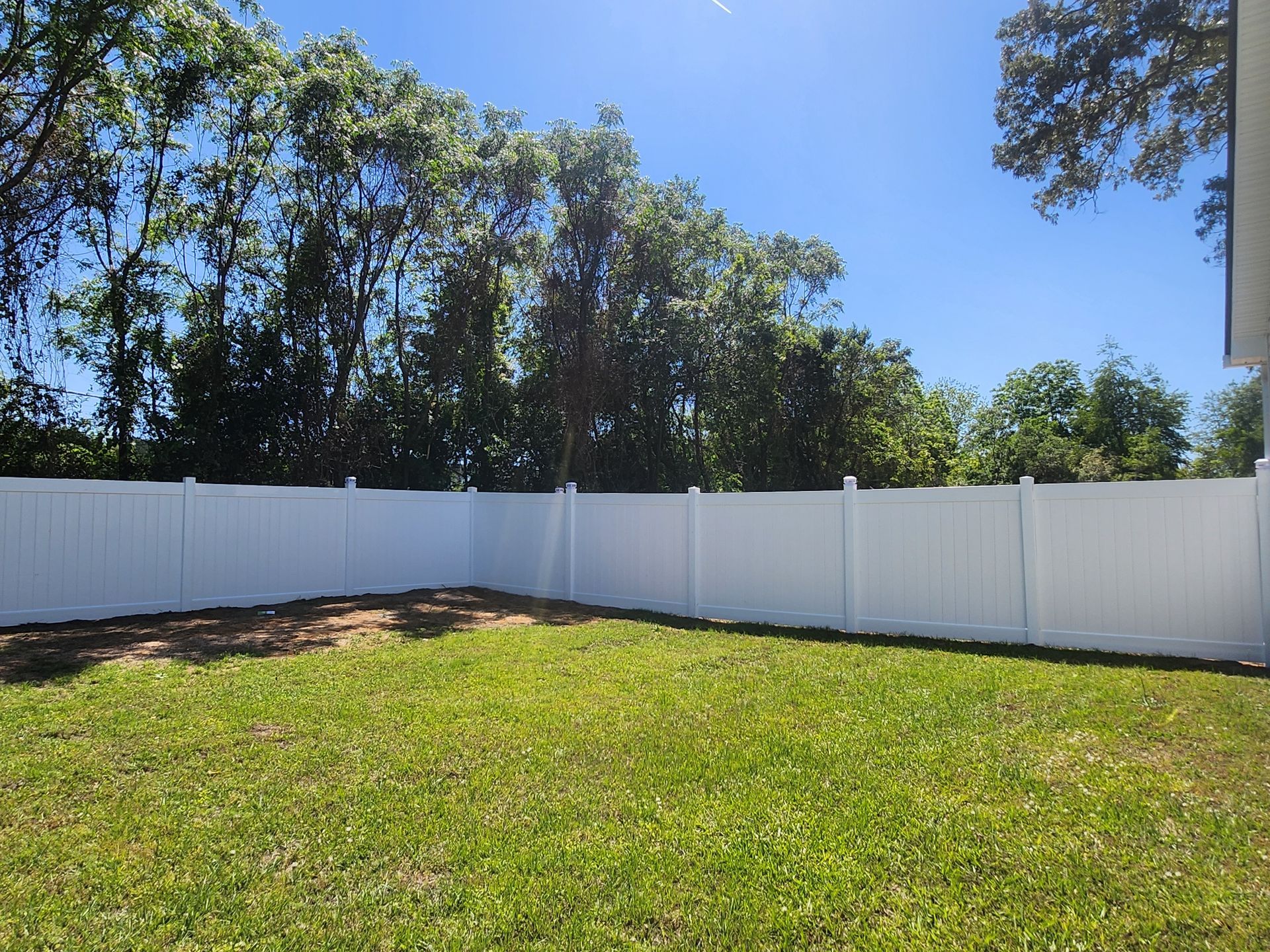 A white fence surrounds a lush green yard.