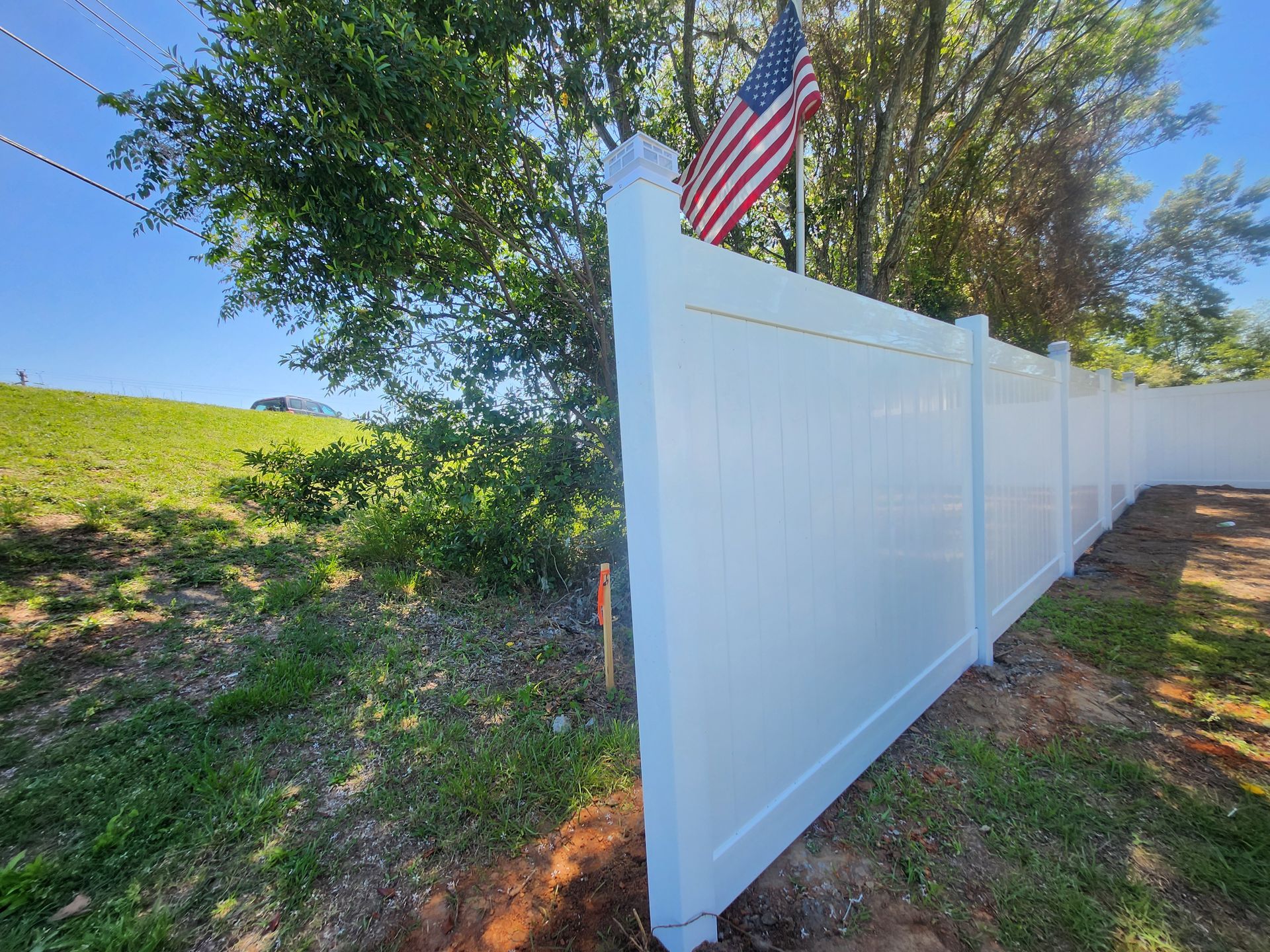 A white fence with an american flag on top of it.