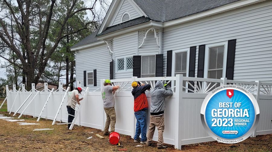 A group of men are installing a fence in front of a house.