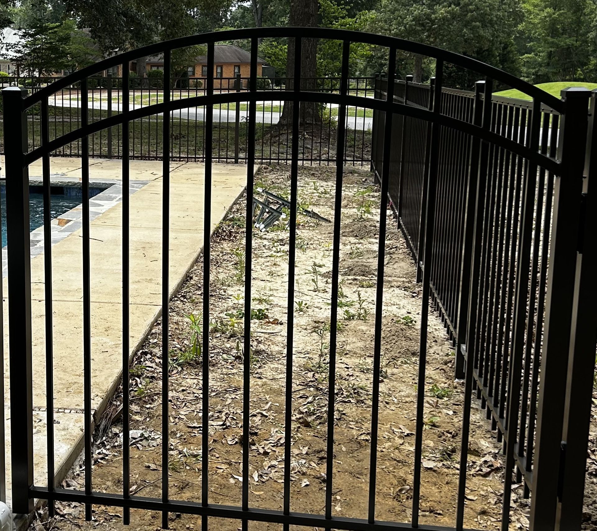 A black wrought iron fence with a white door in the background