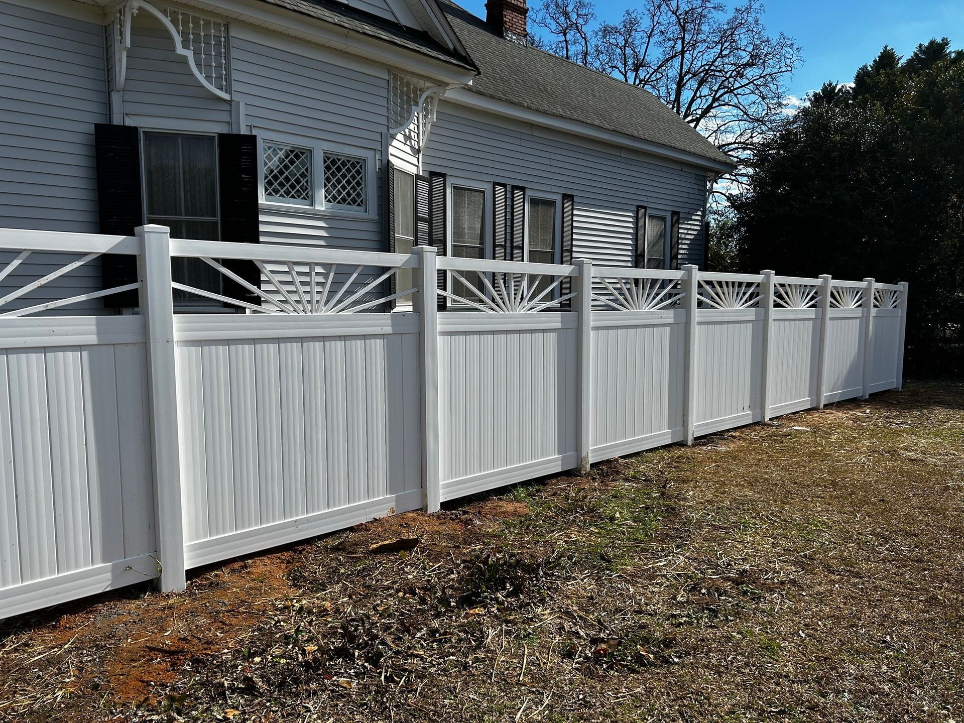 A white picket fence with trees in the background