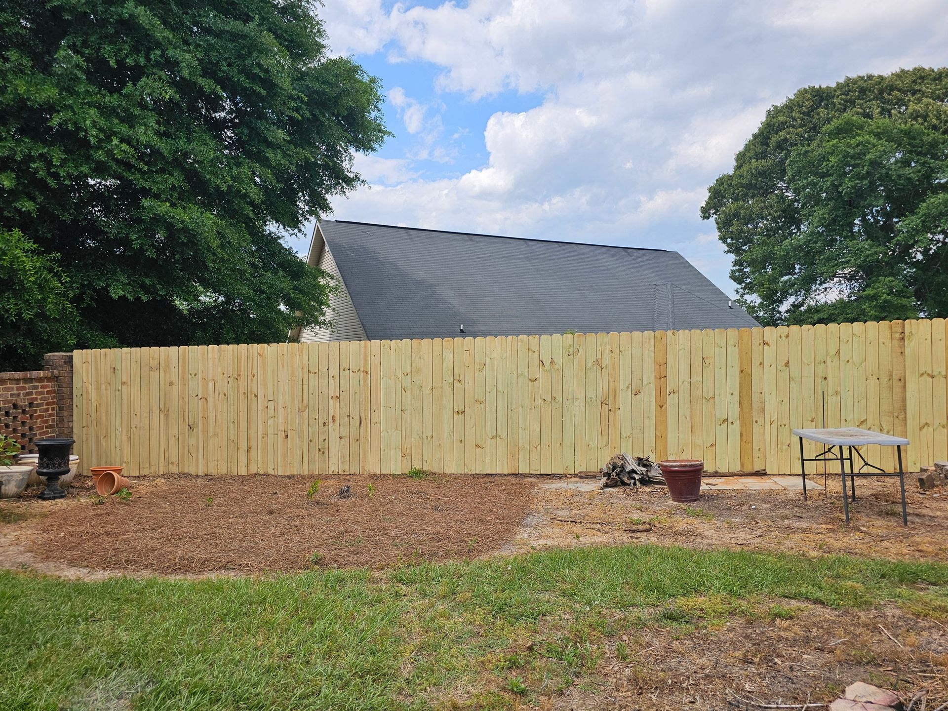 A wooden fence is in the backyard of a house.