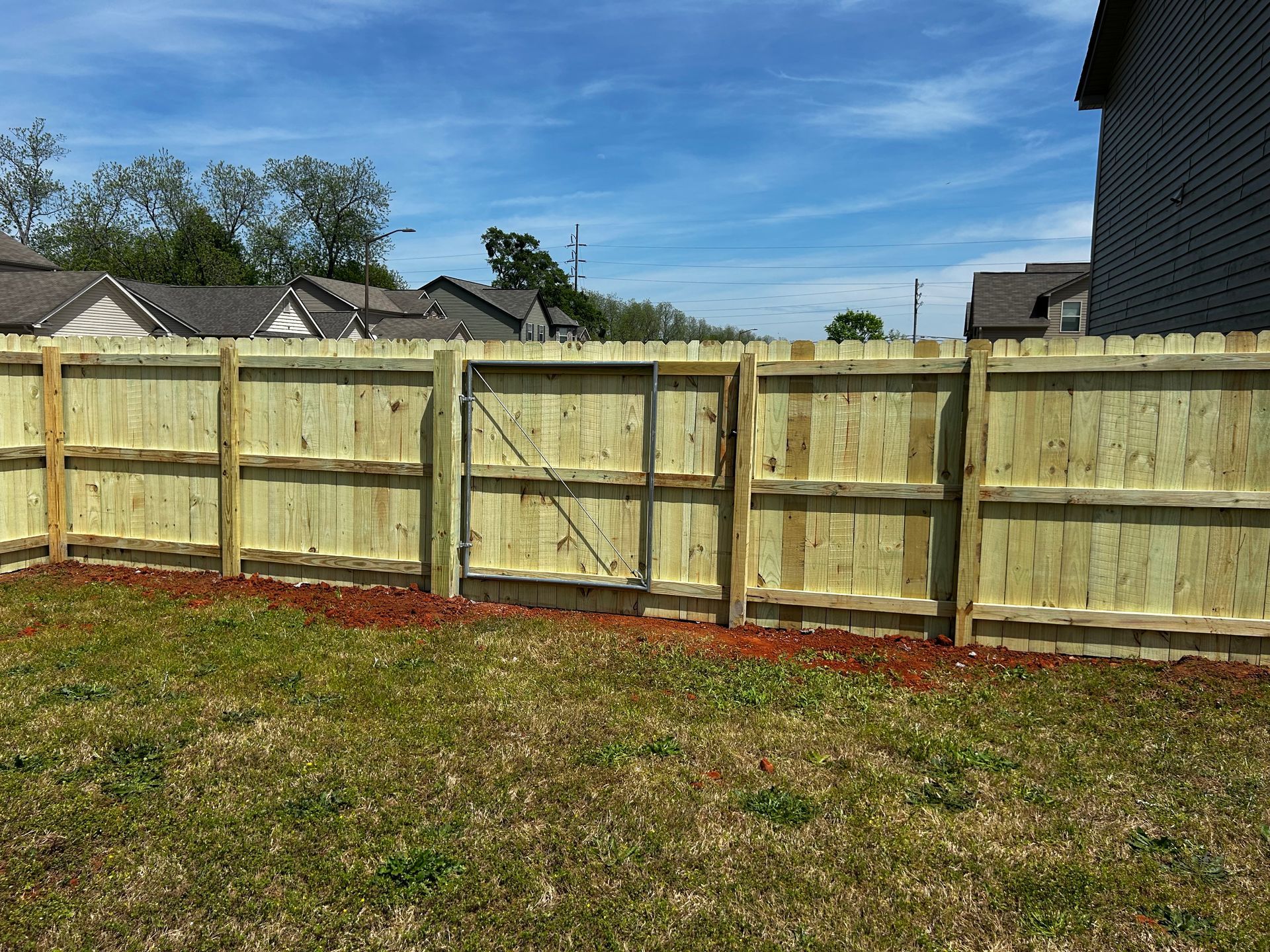 A wooden fence with a gate in the backyard of a house.