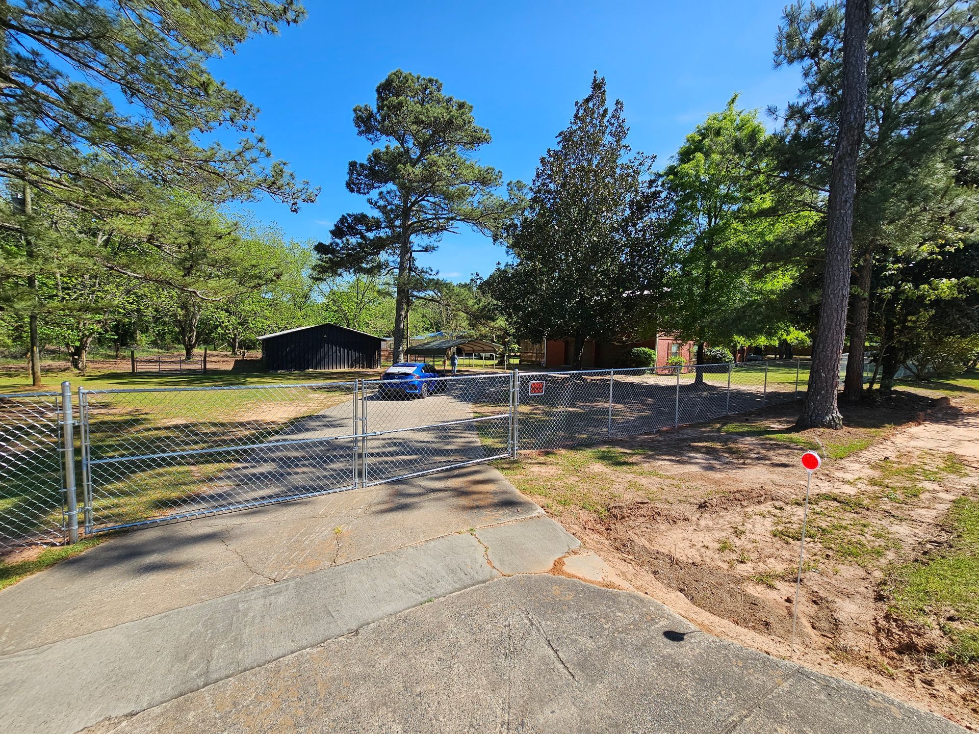 A car is parked on the side of the road in front of a fence.