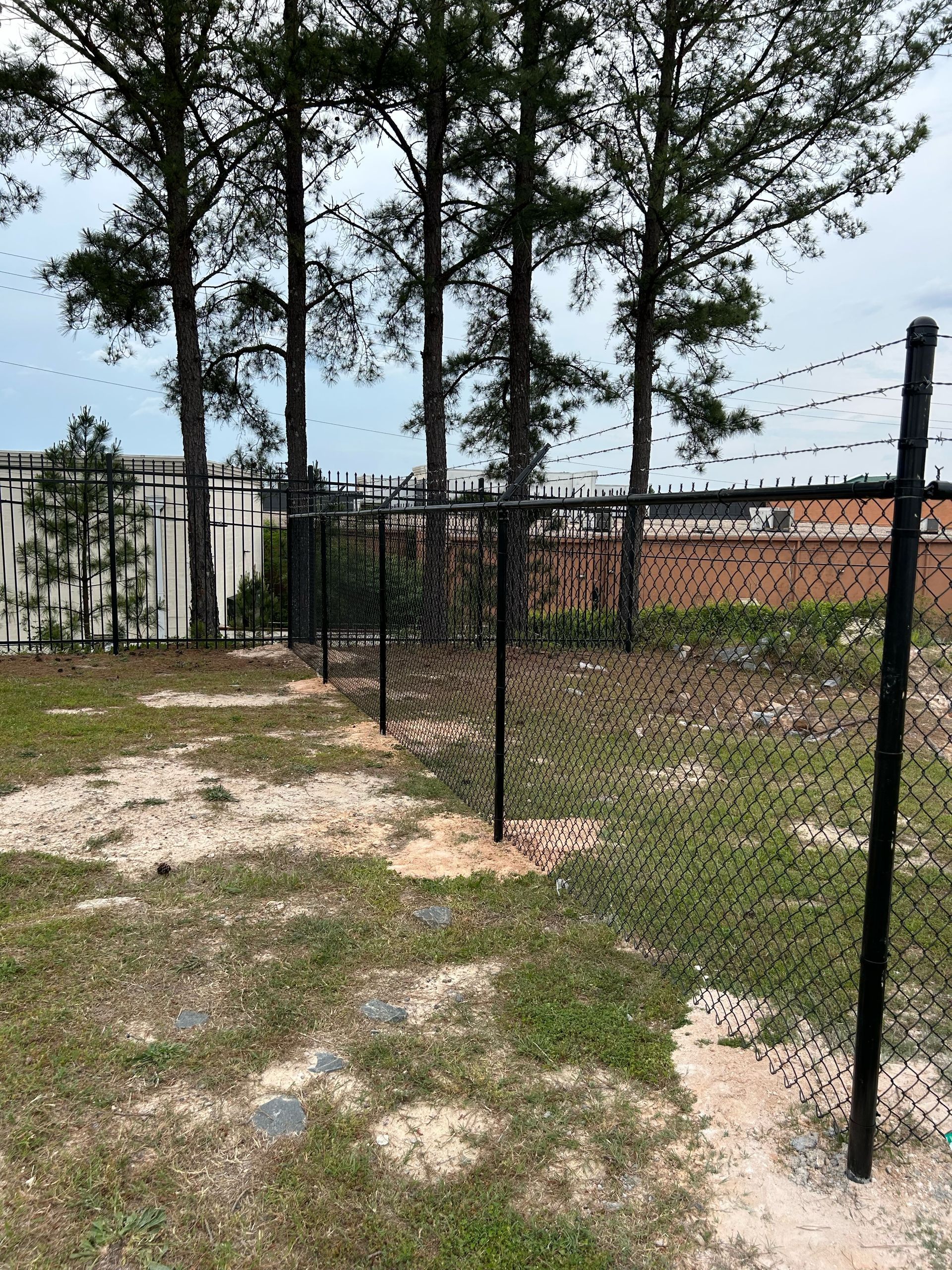 A chain link fence is sitting in the middle of a grassy field.